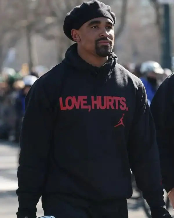 Front view of the Jalen hurts wearing black love hurts hoodie on Jalen Hurts in black with bold red 'LOVE HURTS' text and a small red Jordan logo.