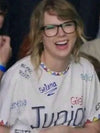 Taylor Swiftwearing a Junior Jewels Shirt with various names printed on it, laughing.