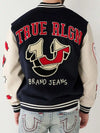 Person wearing a 'True Religion' branded varsity jacket with jeans.