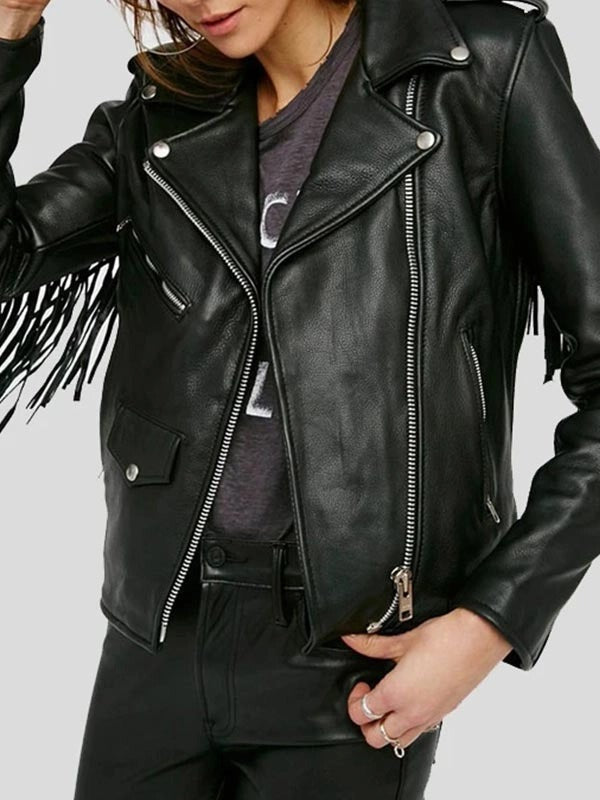 Person wearing a black leather jacket with fringe details on a plain background