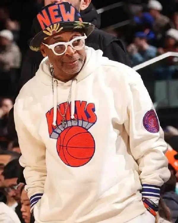 Spike Lee wearing a white Knicks pullover hoodie
